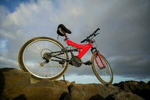 une rouge Montagne bicyclette est séance sur Haut de une rocheux falaise photo