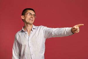 Jeune homme dans une classique blanc chemise est posant plus de une rose Contexte. photo