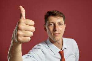 portrait de une Jeune brunet homme posant dans une studio contre une rouge Contexte. photo