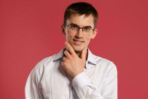 Jeune homme dans une classique blanc chemise est posant plus de une rose Contexte. photo