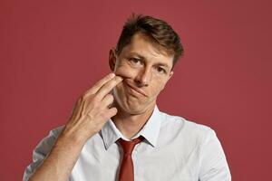 portrait de une Jeune brunet homme posant dans une studio contre une rouge Contexte. photo