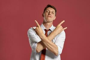 Jeune homme dans une classique blanc chemise et rouge attacher posant plus de une rose Contexte. photo