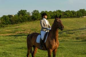 Jeune femme équitation une cheval sur le vert champ photo