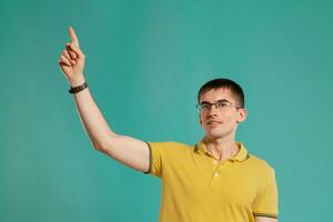 Beau gars dans une Jaune décontractée T-shirt est posant plus de une bleu Contexte. photo