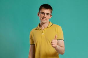 Beau gars dans une Jaune décontractée T-shirt est posant plus de une bleu Contexte. photo