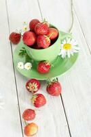 mûr des fraises de le jardin dans une vert agresser avec blanc camomille, été photo