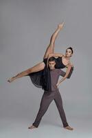 deux athlétique moderne ballet danseurs sont posant contre une gris studio Contexte. photo