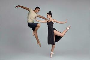 deux athlétique moderne ballet danseurs sont posant contre une gris studio Contexte. photo