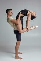 deux athlétique moderne ballet danseurs sont posant contre une gris studio Contexte. photo