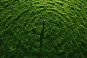 ai généré aérien vue de une homme permanent dans le milieu de une vert champ, Capturer une directement au dessus coup de Frais vert herbe ou pelouse, ai généré photo