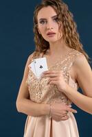 Jeune magnifique femme en portant le gagnant combinaison de poker cartes sur foncé bleu Contexte. deux as photo