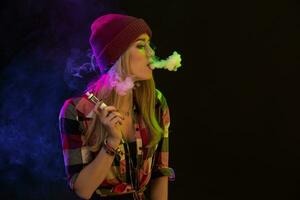 vapoter fille. Jeune branché femme vape e-cig sur noir Contexte. hip hop style. studio coup photo