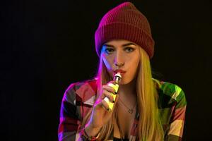 vapoter fille. Jeune branché femme vape e-cig sur studio sur noir Contexte. hip hop style. proche en haut. photo