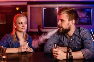 une homme et femme fumeur électronique cigarette dans une vape bar. photo