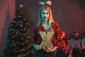 Noël, Noël, Nouveau année, hiver, bonheur concept - souriant femme dans Père Noël assistant chapeau avec une en bois lettre X. photo