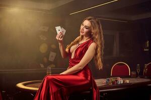 Jeune magnifique femme est posant contre une poker table dans luxe casino. photo