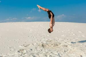 portrait de Jeune Parkour homme Faire retourner ou saut périlleux sur le sable. photo