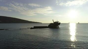 aérien pour détruit navire le long de le rocheux côte contre brillant Soleil. tir. vieux coulé bateau près mer rive sur gros Montagne et bleu ciel Contexte. photo