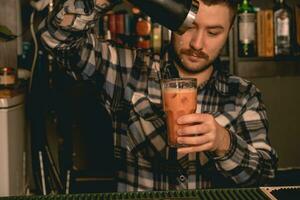 barbu barman verser cocktail de Mixeur dans highball verre photo