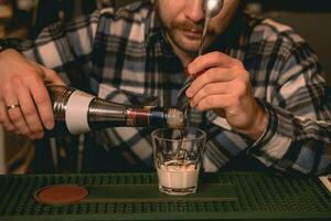 barman verser café liqueur dans verre avec crème tandis que en train de préparer cocktail blanc russe photo