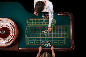 homme croupier et femme en jouant roulette à le table dans le casino. Haut vue à une roulette vert table avec une ruban mesure. photo