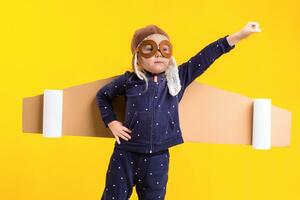 liberté, fille en jouant à être avion pilote, marrant peu fille avec aviateur casquette et lunettes, porte ailes fabriqué de marron papier carton comme un avion photo