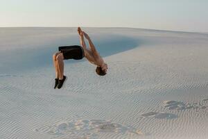 homme étude Parkour sur leur posséder. acrobaties dans le le sable photo