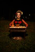 large coup de un asiatique fille dans traditionnel vêtements séance dans une forêt avec une table plein de fleurs photo