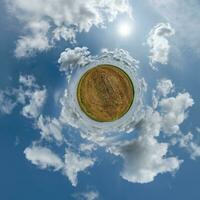 petite planète verte dans un ciel bleu avec de beaux nuages. transformation du panorama sphérique à 360 degrés. vue aérienne abstraite sphérique. courbure de l'espace. photo