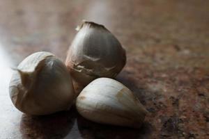 trois gousses d'ail sur un comptoir en marbre marron. la gastronomie. photo