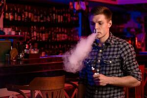 le homme fumée un électronique cigarette à le vape magasin. photo