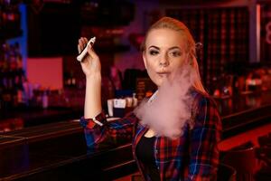 Jeune jolie femme fumée un électronique cigarette à le vape bar photo