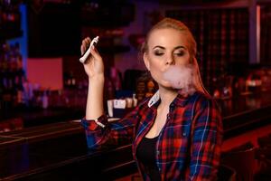 Jeune jolie femme fumée un électronique cigarette à le vape bar photo