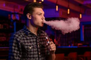 le homme fumée un électronique cigarette à le vape magasin. photo