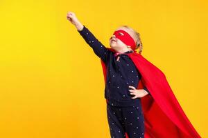 marrant peu Puissance super-héros enfant fille dans une rouge imperméable et une masque. super-héros concept. photo