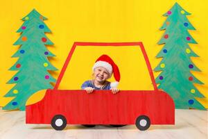 enfant avec Noël chapeau conduite une voiture fabriqué de papier carton. Noël concept. Nouveau années vacances. photo