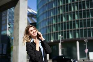 heureux femme d'affaires fête sur rue, parlant sur mobile téléphone, recevoir bien nouvelles sur appel photo