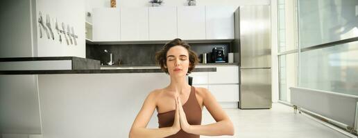 proche en haut portrait de Jeune femme à maison, séance et méditer, entraine toi yoga, fabrication lotus pose, exercice à l'intérieur photo