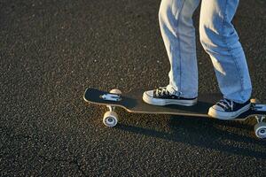 tondu coup de jambes sur longboard. patineur fille équitation sa planche à roulette sur rue. femelle adolescent sur croiseur photo