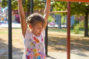 une de bonne humeur enfant fille est travail en dehors sur le horizontal bar, des sports appareil photo