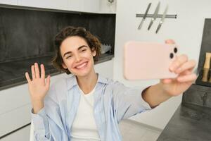 content, magnifique brunette fille prend selfie à maison, pose pour photo avec téléphone intelligent