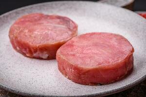 rond forme steaks de brut juteux thon avec sel et épices photo