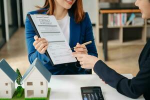 agent de courtage immobilier présentant et consultant le client pour la prise de décision signant un accord de formulaire d'assurance, modèle de maison, concernant l'offre de prêt hypothécaire photo