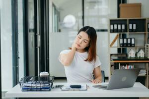 femme qui est fatiguée et qui réfléchit trop après avoir travaillé avec une tablette et un ordinateur portable au bureau. photo