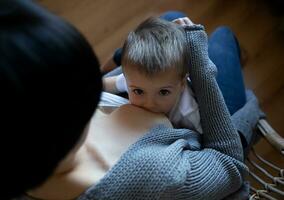 Jeune femme allaitement maternel sa peu fils tandis que séance dans une confortable fauteuil photo