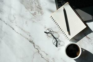 Haut vue au dessus de marbre modèle bureau avec clavier ordinateur, carnet et café tasse avec équipement autre Bureau fournitures. affaires et la finance concept. lieu de travail, avec Vide copie espace moquer en haut photo