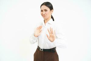 arrêt, rester dos. Jeune asiatique femme rejette qch, tire loin, détient mains élargi à refuser, désapprouver quelque chose, blanc Contexte photo