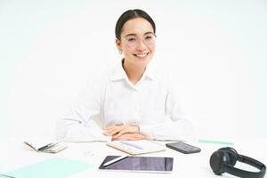 Bureau travail et entreprise. Jeune professionnel femelle employeur, équipe chef séance à lieu de travail avec numérique tablette, souriant à caméra, blanc Contexte photo