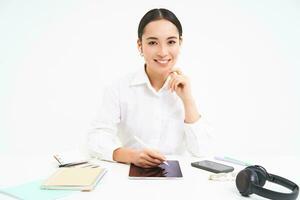 Jeune femme d'affaires est assis dans sa Bureau et écrit sur numérique tablette, travail dans sa entreprise, isolé sur blanc Contexte photo