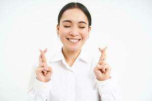 Japonais femme d'affaires traverser les doigts pour bien chance, fait du souhait, a haute espoirs, anticipe qch, des stands plus de blanc Contexte photo